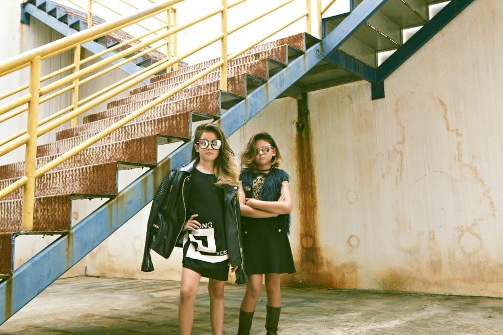 Keia Lo (L): Leather jacket, Burberry Brit. Shirt (worn as dress), Young Versace. Sunglasses, model's own. Elie Lo (R): Dress, Young Versace. Gilet; sunglasses; and choker, all model's own.