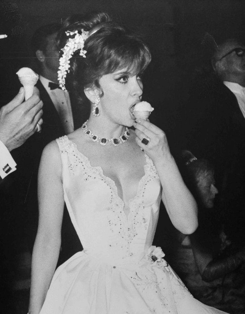 10 Jun 1966, Monte Carlo, Monaco --- Original caption: It's always a refreshing sight watching actress Gina Lollobrigida refreshing herself. Here, she munches little-girl style on an ice cream cone at the Monaco Centenary Ball. But as her fashion emphasizes, Gina is no little girl. Indeed. --- Image by © Bettmann/CORBIS