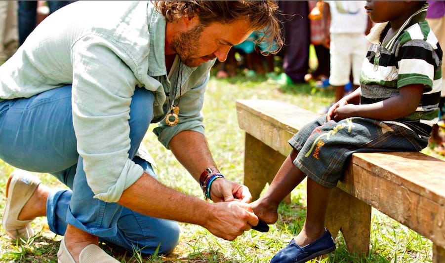 Toms Founder, Blake Mycoskie Giving shoes to a child in need, an act that has become a celebrated ritual.