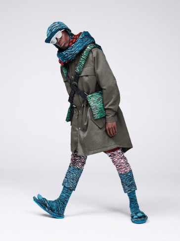 KO EBOMBO (musician and performance artist, based in Paris, front-man of the band 19) wears a parka with removable printed collar, block colour tiger print jeans, and the padded flip-flops with tabi socks. Oko also wears the tiger-printed cap with attached scarf, a printed woven scarf and the tiger-printed cross-body bag